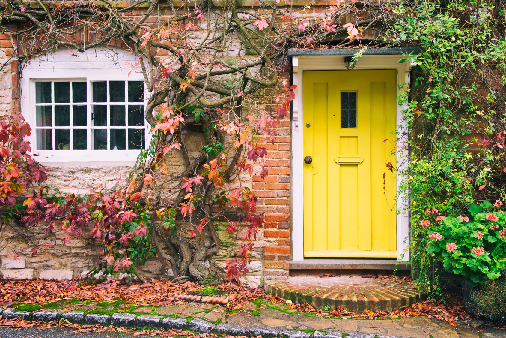 english country home with yellow door in autumn